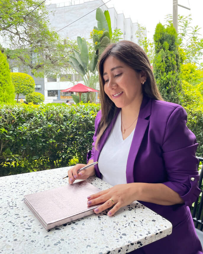 Gina Gonzales sentada en un jardín tomando notas en su libreta.